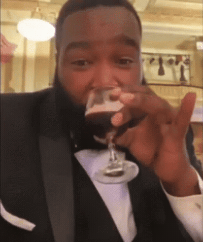 A Man In A Tuxedo Drinking From A Glass GIF