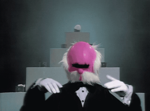 A Man In A Tuxedo Has A Pink Mask On His Head GIF