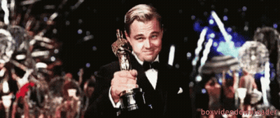 A Man In A Tuxedo Holding An Oscar Statue GIF