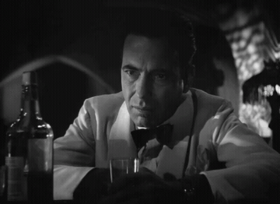 A Man In A Tuxedo Holds A Glass And A Bottle GIF