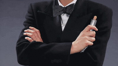 A Man In A Tuxedo Holds A Lighter In His Hand GIF