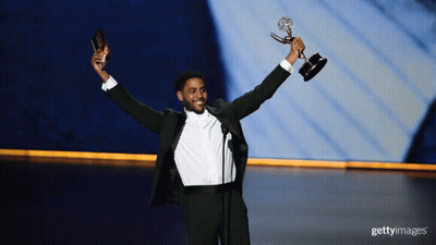 A Man In A Tuxedo Holds A Trophy In His Hands GIF