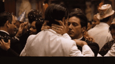 A Man In A Tuxedo Holds Another Man 'S Neck In A Crowd GIF