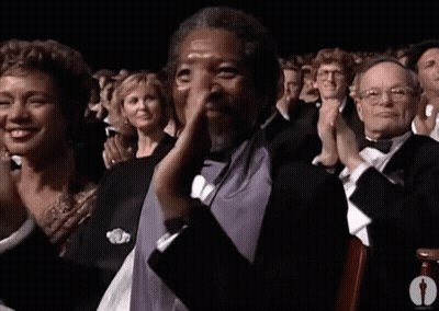 A Man In A Tuxedo Is Applauding In Front Of A Crowd GIF