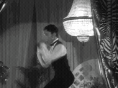 A Man In A Tuxedo Is Dancing In A Black And White Photo GIF