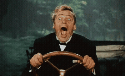A Man In A Tuxedo Is Driving A Car And Making A Funny Face GIF