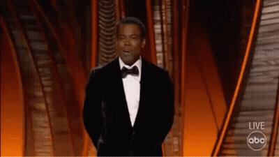 A Man In A Tuxedo Is Giving A Speech On A Stage . GIF