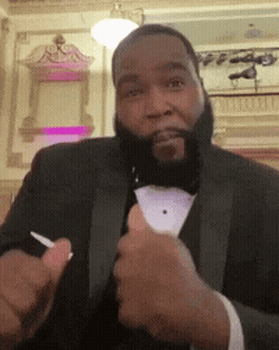 A Man In A Tuxedo Is Giving A Thumbs Up Sign GIF