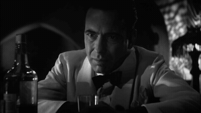 A Man In A Tuxedo Is Holding A Glass And A Bottle Of Whiskey GIF