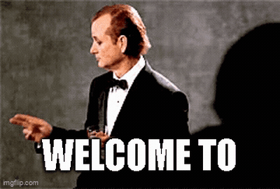 A Man In A Tuxedo Is Holding A Glass Of Whiskey And Pointing At Someone . GIF