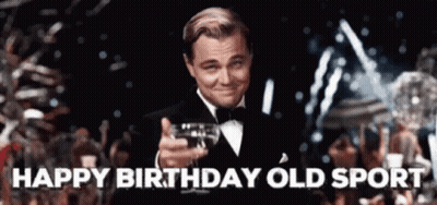 A Man In A Tuxedo Is Holding A Glass Of Wine In His Hand And Says Happy Birthday Old Sport . GIF