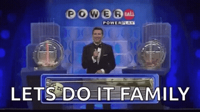 A Man In A Tuxedo Is Holding A Microphone In Front Of A Powerball Lottery Machine . GIF