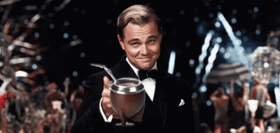 A Man In A Tuxedo Is Holding A Silver Cup With A Straw In It GIF