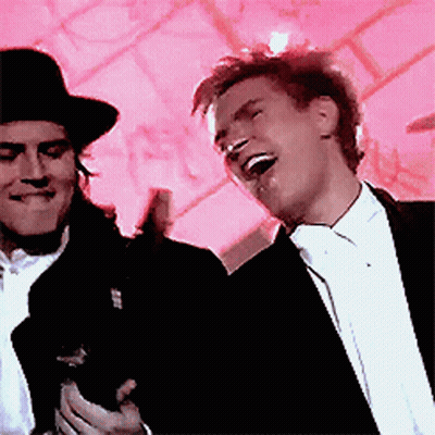 A Man In A Tuxedo Is Laughing Next To Another Man In A Top Hat GIF