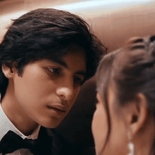 A Man In A Tuxedo Is Looking At A Woman In A White Shirt GIF