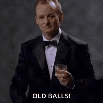 A Man In A Tuxedo Is Pointing At The Camera While Holding A Glass Of Whiskey . GIF