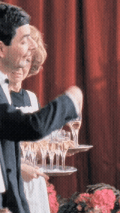 A Man In A Tuxedo Is Pouring Champagne Into A Tray GIF