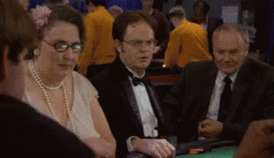 A Man In A Tuxedo Is Sitting At A Table With Other People Playing Poker . GIF