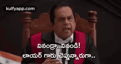 A Man In A Tuxedo Is Sitting In A Chair Holding A Gavel And Giving A Thumbs Up . GIF