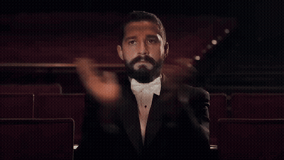 A Man In A Tuxedo Is Sitting In An Auditorium GIF