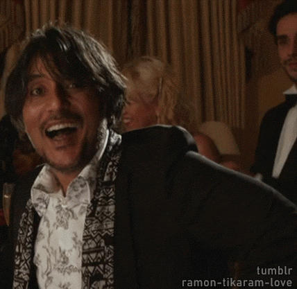 A Man In A Tuxedo Is Smiling And Waving At Someone . GIF