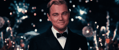 A Man In A Tuxedo Is Smiling In Front Of A Crowd GIF