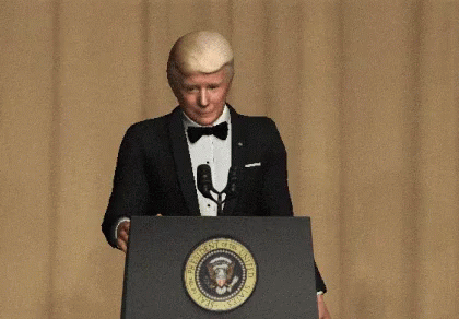 A Man In A Tuxedo Is Standing At A Podium With The Seal Of The President Of The United States On It GIF