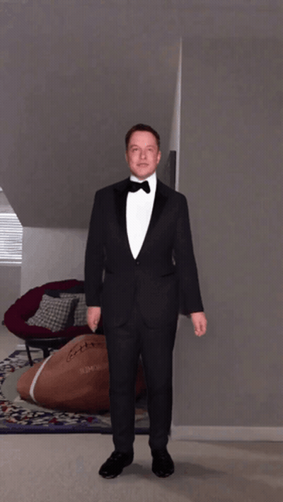 A Man In A Tuxedo Is Standing In A Room With A Football On The Floor GIF