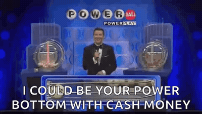A Man In A Tuxedo Is Standing In Front Of A Power Ball Lottery Machine . GIF