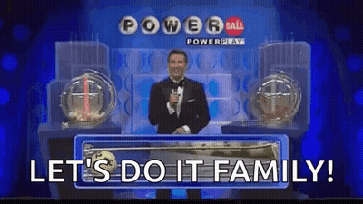A Man In A Tuxedo Is Standing On A Stage In Front Of A Powerball Lottery Machine . GIF