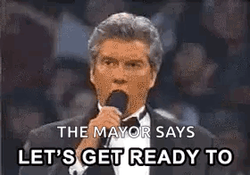 A Man In A Tuxedo Is Talking Into A Microphone And Says `` The Mayor Says Let 'S Get Ready To '' GIF