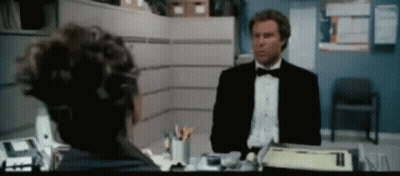 A Man In A Tuxedo Is Talking To Another Man In A Cubicle GIF