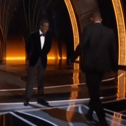 A Man In A Tuxedo Shakes Hands With Another Man In A Suit GIF