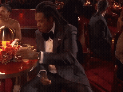A Man In A Tuxedo Sits At A Table GIF
