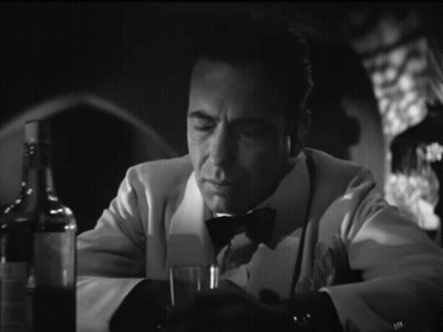 A Man In A Tuxedo Sits At A Table With A Glass Of Wine GIF