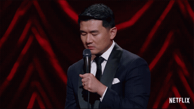 A Man In A Tuxedo Stands In Front Of A Microphone With Netflix Written On The Bottom GIF