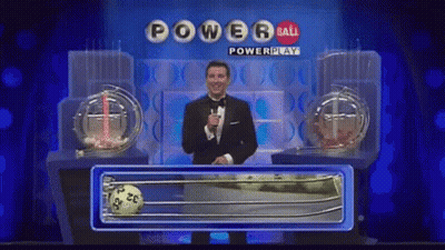 A Man In A Tuxedo Stands In Front Of A Powerball Lottery Machine GIF