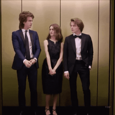 A Man In A Tuxedo Stands Next To A Woman In A Black Dress And A Man In A Bow Tie GIF