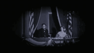 A Man In A Tuxedo Stands Next To A Woman In A Dress And A Man In A Suit GIF
