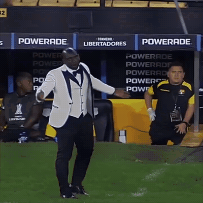 A Man In A Tuxedo Stands On A Soccer Field In Front Of A Powerade Advertisement GIF
