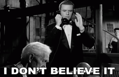 A Man In A Tuxedo Talking On A Phone With The Words " I Don 'T Believe It " Behind Him GIF