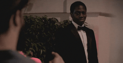 A Man In A Tuxedo Talks To Another Man In A Pink Shirt GIF