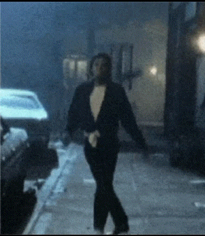 A Man In A Tuxedo Walking Down A Street GIF
