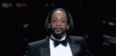 A Man In A Tuxedo With A Beard Is Making A Funny Face . GIF