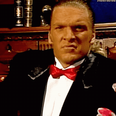 A Man In A Tuxedo With A Red Bow Tie Is Looking At Something GIF