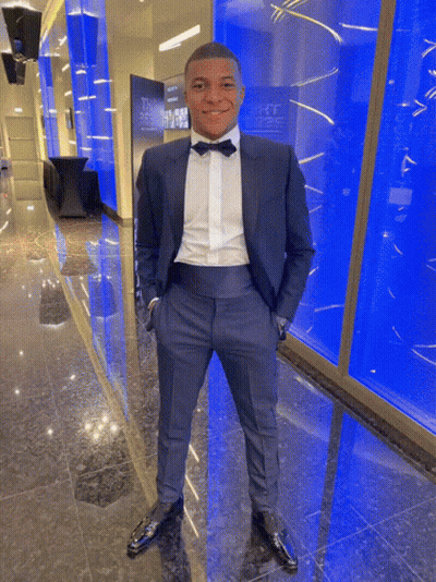 A Man In A Tuxedo With His Hands In His Pockets Stands In Front Of A Wall That Says ' The ' On It GIF