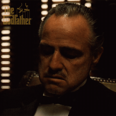 A Man In A Tuxedo With The Godfather Written On His Head GIF