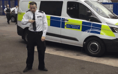 A Man In A Uniform Stands In Front Of A White Van That Says Newcastle Police GIF