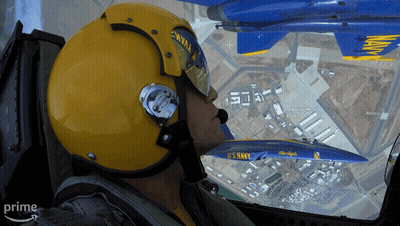 A Man In A Us Navy Helmet Looks Out The Window Of A Plane GIF