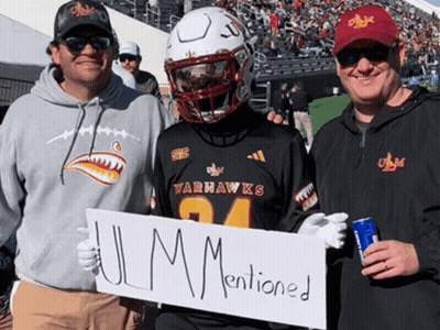 A Man In A Varhawks Jersey Holds A Sign That Says " Ulm Mentioned " GIF